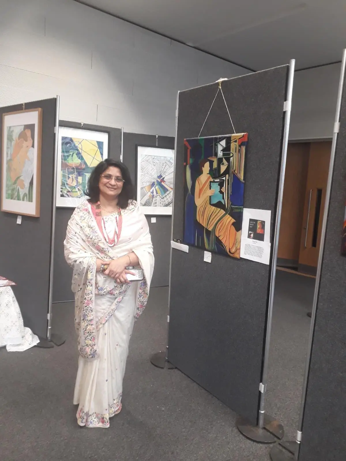 Millie Basu-Roy standing beside her artwork at an exhibition